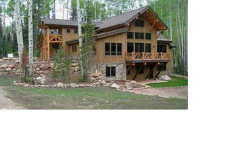 large wood-frame house surrounded by woods